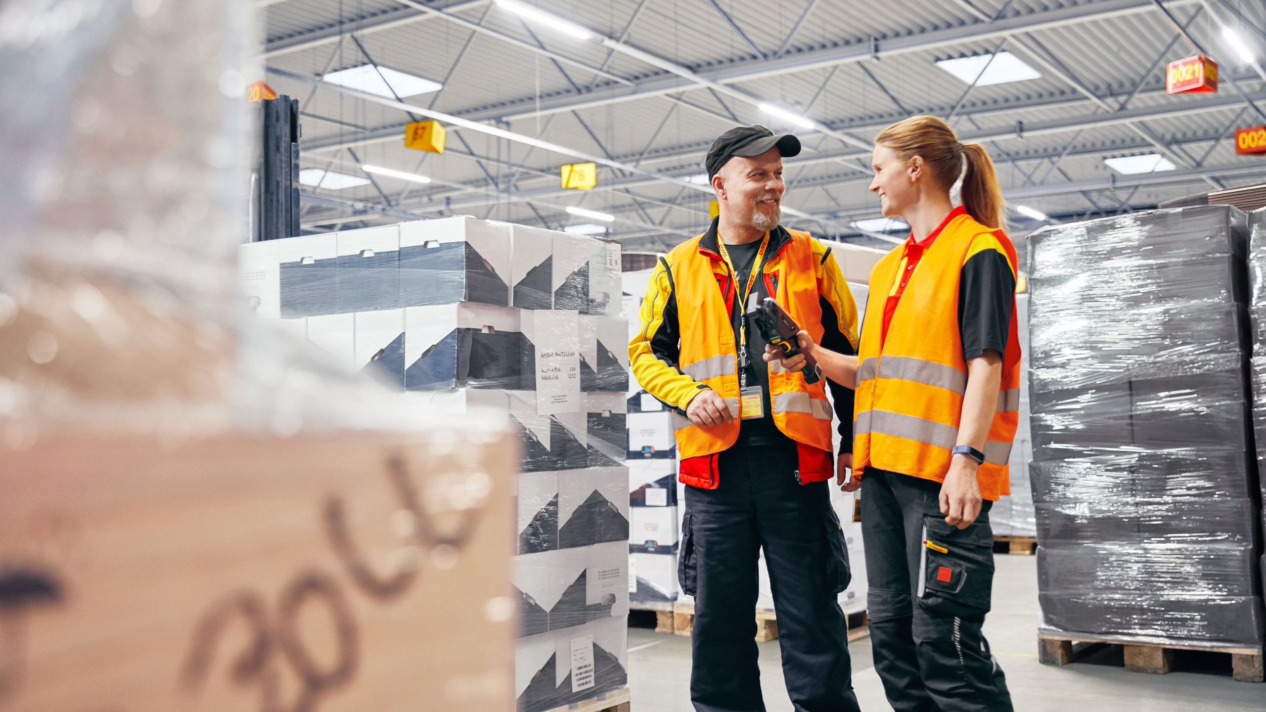 Two DHL employees talking, scanners in hand