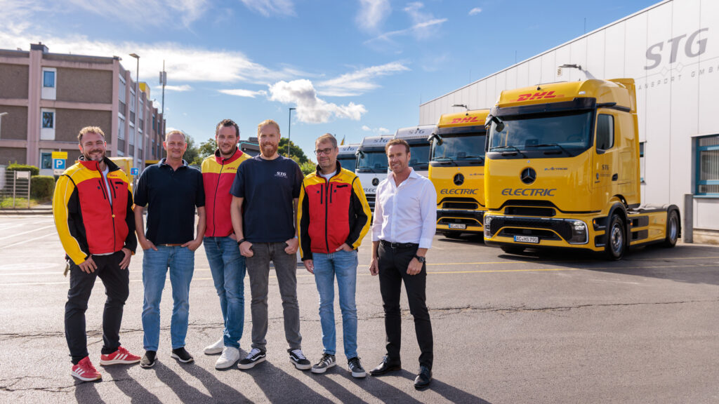 Mitarbeiter von DHL Freight und Partner STG vor den neuen Mercedes eActros